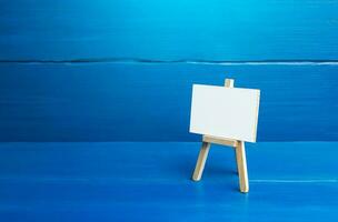 An easel with a white board on a blue background. Presentations, brainstorming, teaching, or artistic expression. Strategy planning at meetings and briefings photo