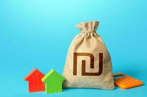 Israeli shekel money bag and small houses. Property appraisal, realtor services. Investments in real estate. Bank offer of mortgage loan. Sale of housing. Buy. Rental business. Fair market price photo
