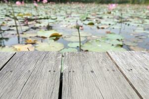 Wooden table behind blurred lotus pond on nature background photo