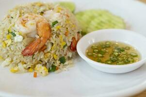 Shrimp fried rice on a white plate with fish sauce chili in a cup photo