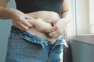 Close up of a belly with scar from c-section and abdominal fat. Women's health. A woman dressed up in sportswear demonstrating her imperfect body after a childbirth with nursery on the background. photo