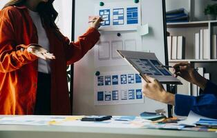 Close up ux developer and ui designer brainstorming about mobile app interface wireframe design on table with customer breif and color code at modern office.Creative digital development agency photo