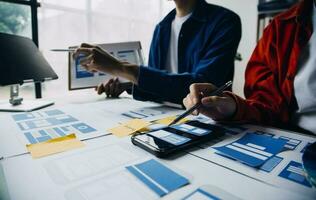 Close up ux developer and ui designer brainstorming about mobile app interface wireframe design on table with customer breif and color code at modern office.Creative digital development agency photo