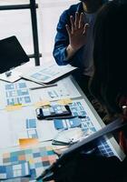 Close up ux developer and ui designer brainstorming about mobile app interface wireframe design on table with customer breif and color code at modern office.Creative digital development agency photo
