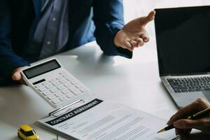 A car rental company employee is handing out the car keys to the renter after discussing the rental details and conditions together with the renter signing a car rental agreement. Concept car rental. photo