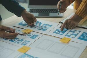 Close up ux developer and ui designer brainstorming about mobile app interface wireframe design on table with customer breif and color code at modern office.Creative digital development agency photo