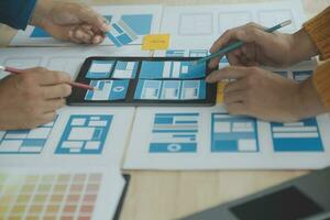 Close up ux developer and ui designer brainstorming about mobile app interface wireframe design on table with customer breif and color code at modern office.Creative digital development agency photo