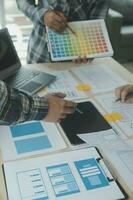 Close up ux developer and ui designer brainstorming about mobile app interface wireframe design on table with customer breif and color code at modern office.Creative digital development agency photo