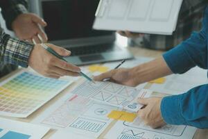 Close up ux developer and ui designer brainstorming about mobile app interface wireframe design on table with customer breif and color code at modern office.Creative digital development agency photo