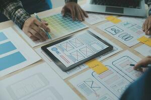 Close up ux developer and ui designer brainstorming about mobile app interface wireframe design on table with customer breif and color code at modern office.Creative digital development agency photo