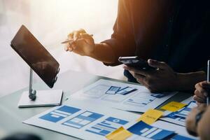 Close up ux developer and ui designer brainstorming about mobile app interface wireframe design on table with customer breif and color code at modern office.Creative digital development agency photo