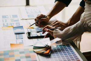 Close up ux developer and ui designer brainstorming about mobile app interface wireframe design on table with customer breif and color code at modern office.Creative digital development agency photo