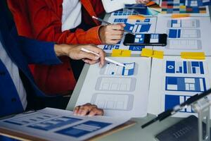 Close up ux developer and ui designer brainstorming about mobile app interface wireframe design on table with customer breif and color code at modern office.Creative digital development agency photo