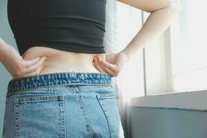 Close up of a belly with scar from c-section and abdominal fat. Women's health. A woman dressed up in sportswear demonstrating her imperfect body after a childbirth with nursery on the background. photo