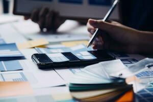 Close up ux developer and ui designer brainstorming about mobile app interface wireframe design on table with customer breif and color code at modern office.Creative digital development agency photo