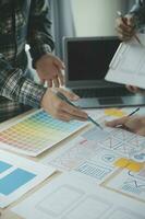 Close up ux developer and ui designer brainstorming about mobile app interface wireframe design on table with customer breif and color code at modern office.Creative digital development agency photo