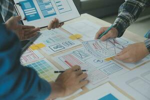 Close up ux developer and ui designer brainstorming about mobile app interface wireframe design on table with customer breif and color code at modern office.Creative digital development agency photo