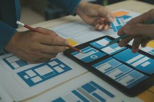 Close up ux developer and ui designer brainstorming about mobile app interface wireframe design on table with customer breif and color code at modern office.Creative digital development agency photo