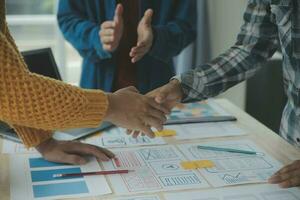 Close up ux developer and ui designer brainstorming about mobile app interface wireframe design on table with customer breif and color code at modern office.Creative digital development agency photo