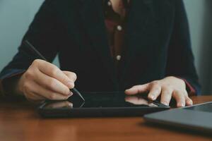 mujer de negocios asiática que usa una computadora portátil y trabaja en la oficina con un documento de calculadora en el escritorio, planificando el análisis del informe financiero, la inversión del plan de negocios, el concepto de análisis financiero. foto