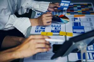 Close up ux developer and ui designer brainstorming about mobile app interface wireframe design on table with customer breif and color code at modern office.Creative digital development agency photo