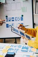 Close up ux developer and ui designer brainstorming about mobile app interface wireframe design on table with customer breif and color code at modern office.Creative digital development agency photo