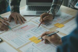 Close up ux developer and ui designer brainstorming about mobile app interface wireframe design on table with customer breif and color code at modern office.Creative digital development agency photo