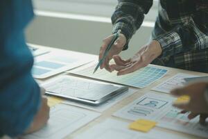 Close up ux developer and ui designer brainstorming about mobile app interface wireframe design on table with customer breif and color code at modern office.Creative digital development agency photo