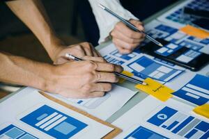 Close up ux developer and ui designer brainstorming about mobile app interface wireframe design on table with customer breif and color code at modern office.Creative digital development agency photo