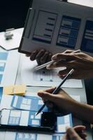 Close up ux developer and ui designer brainstorming about mobile app interface wireframe design on table with customer breif and color code at modern office.Creative digital development agency photo