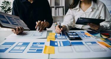 Close up ux developer and ui designer brainstorming about mobile app interface wireframe design on table with customer breif and color code at modern office.Creative digital development agency photo