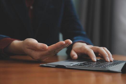 mujer de negocios asiática que usa una computadora portátil y trabaja en la oficina con un documento de calculadora en el escritorio, planificando el análisis del informe financiero, la inversión del plan de negocios, el concepto de análisis financiero. foto