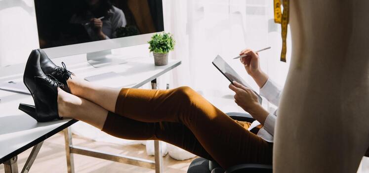 Moda diseñador l joven asiático mujer trabajando utilizando computadora portátil, tableta y sonriente mientras en pie en taller respondiendo en negocio foto