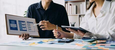 Close up ux developer and ui designer brainstorming about mobile app interface wireframe design on table with customer breif and color code at modern office.Creative digital development agency photo