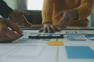 Close up ux developer and ui designer brainstorming about mobile app interface wireframe design on table with customer breif and color code at modern office.Creative digital development agency photo