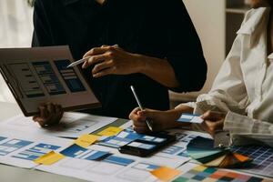 Close up ux developer and ui designer brainstorming about mobile app interface wireframe design on table with customer breif and color code at modern office.Creative digital development agency photo