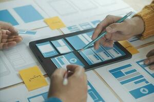 Close up ux developer and ui designer brainstorming about mobile app interface wireframe design on table with customer breif and color code at modern office.Creative digital development agency photo