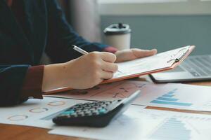 Group of confident business people point to graphs and charts to analyze market data, balance sheet, account, net profit to plan new sales strategies to increase production capacity. photo