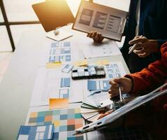 Close up ux developer and ui designer brainstorming about mobile app interface wireframe design on table with customer breif and color code at modern office.Creative digital development agency photo