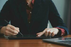 mujer de negocios asiática que usa una computadora portátil y trabaja en la oficina con un documento de calculadora en el escritorio, planificando el análisis del informe financiero, la inversión del plan de negocios, el concepto de análisis financiero. foto