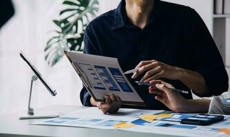 Close up ux developer and ui designer brainstorming about mobile app interface wireframe design on table with customer breif and color code at modern office.Creative digital development agency photo