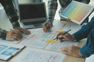 Close up ux developer and ui designer brainstorming about mobile app interface wireframe design on table with customer breif and color code at modern office.Creative digital development agency photo