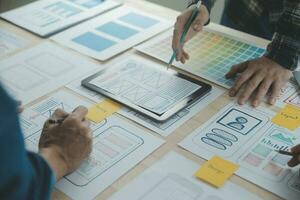 Close up ux developer and ui designer brainstorming about mobile app interface wireframe design on table with customer breif and color code at modern office.Creative digital development agency photo