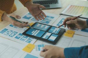 Close up ux developer and ui designer brainstorming about mobile app interface wireframe design on table with customer breif and color code at modern office.Creative digital development agency photo