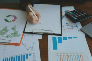 Group of confident business people point to graphs and charts to analyze market data, balance sheet, account, net profit to plan new sales strategies to increase production capacity. photo