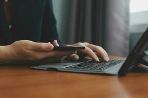 Asian Businesswoman Using laptop computer and working at office with calculator document on desk, doing planning analyzing the financial report, business plan investment, finance analysis concept. photo