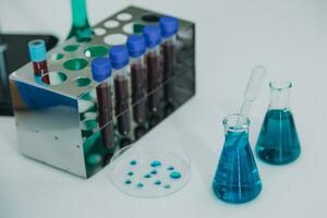 medical or scientific researcher researching and experimenting Multi-colored solution, vial and microscope In the laboratory or in the laboratory by wearing blue gloves and white clothing completely. photo