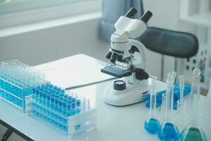 biochemical research scientist team working with microscope for coronavirus vaccine development in pharmaceutical research labolatory, selective focus photo