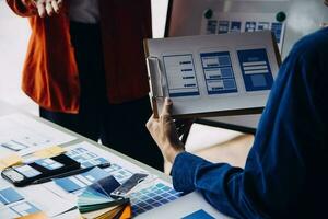 Close up ux developer and ui designer brainstorming about mobile app interface wireframe design on table with customer breif and color code at modern office.Creative digital development agency photo