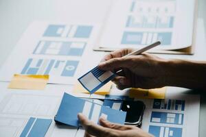 Close up ux developer and ui designer brainstorming about mobile app interface wireframe design on table with customer breif and color code at modern office.Creative digital development agency photo